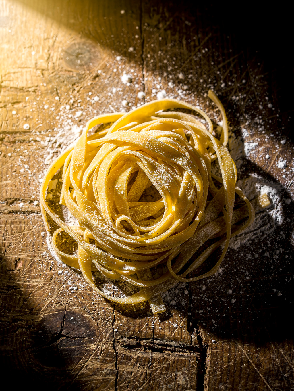 Freshly hand-kneaded tagliatelle pasta dusted with semolina flour on marble